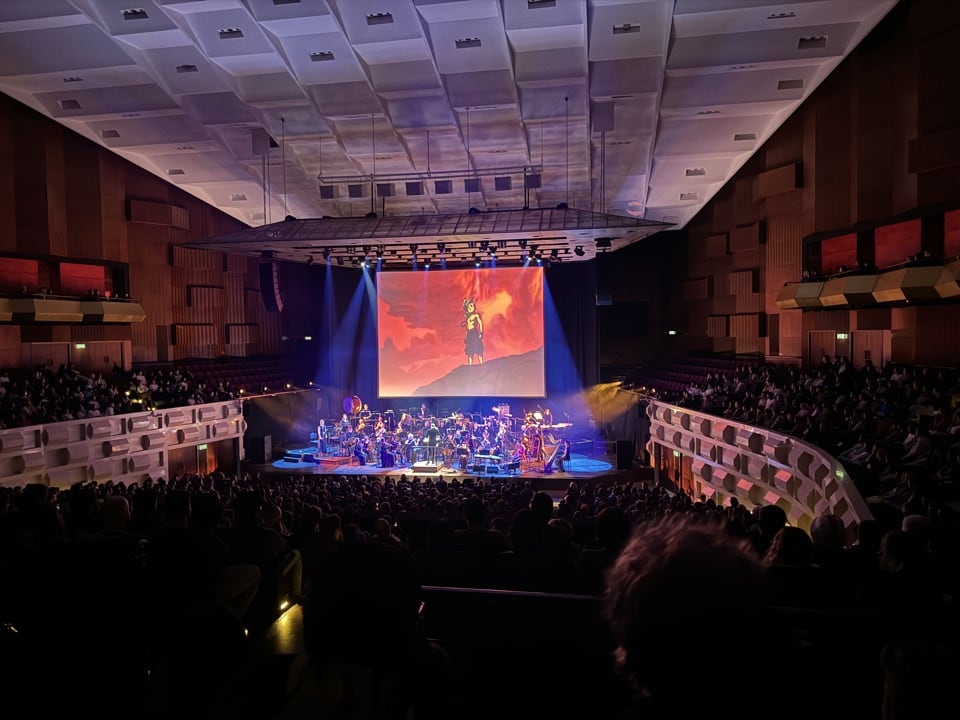 A live orchestra performing music from Avatar: The Last Airbender on stage, with a scene from the show playing on a projected screen above them