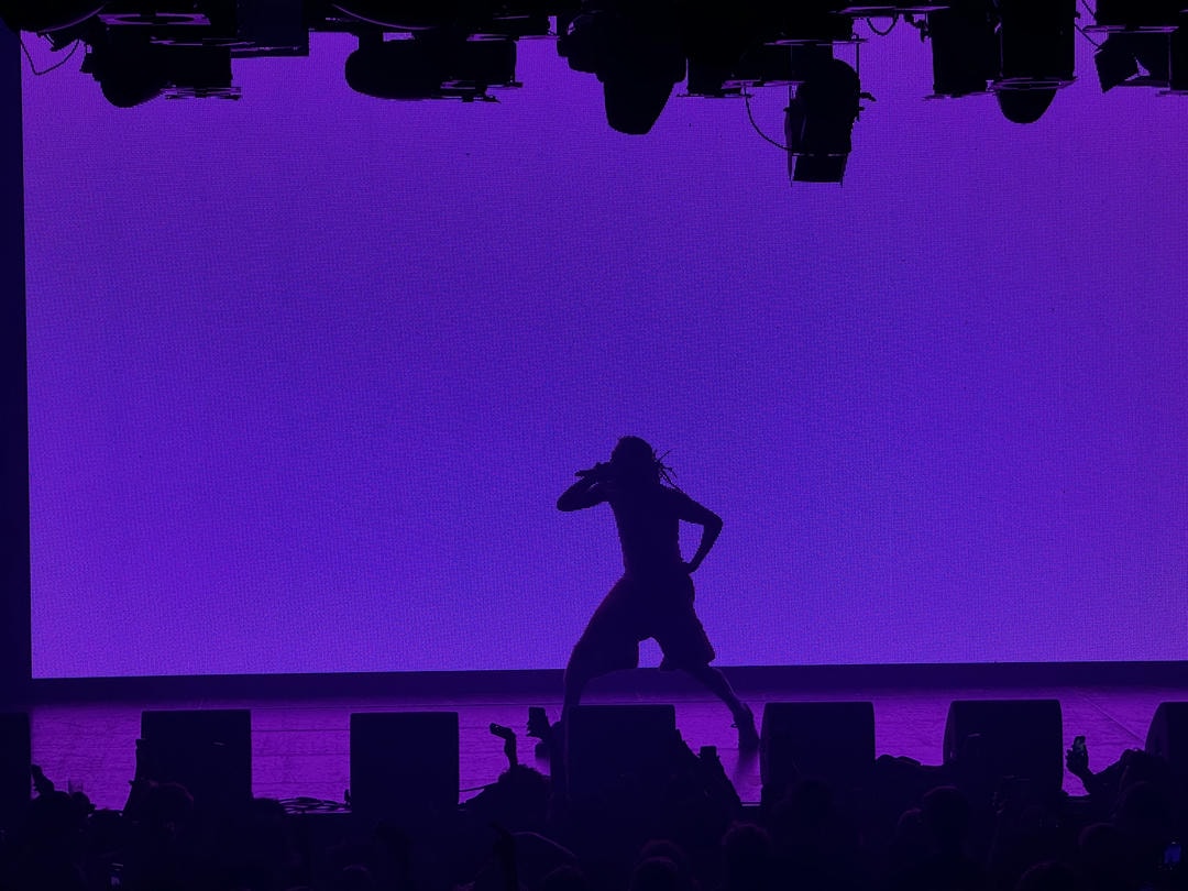 Amin&eacute;'s silhouette backlit by a purple LED screen.